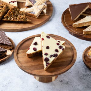 a white-topped cake slice with dried cranberries on a wooden board