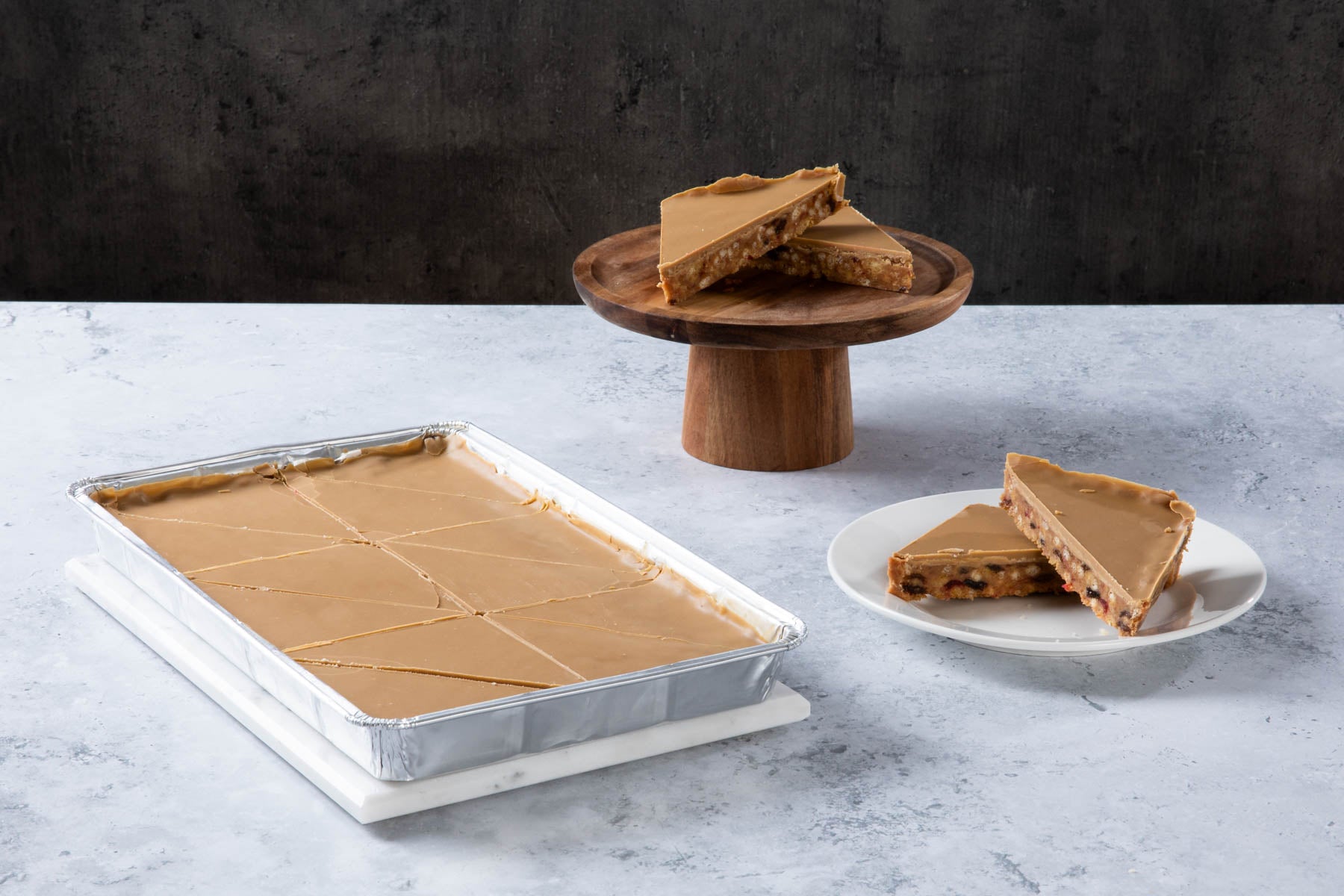 Caramel shortbread slices with caramel topping on a wooden stand and plate.