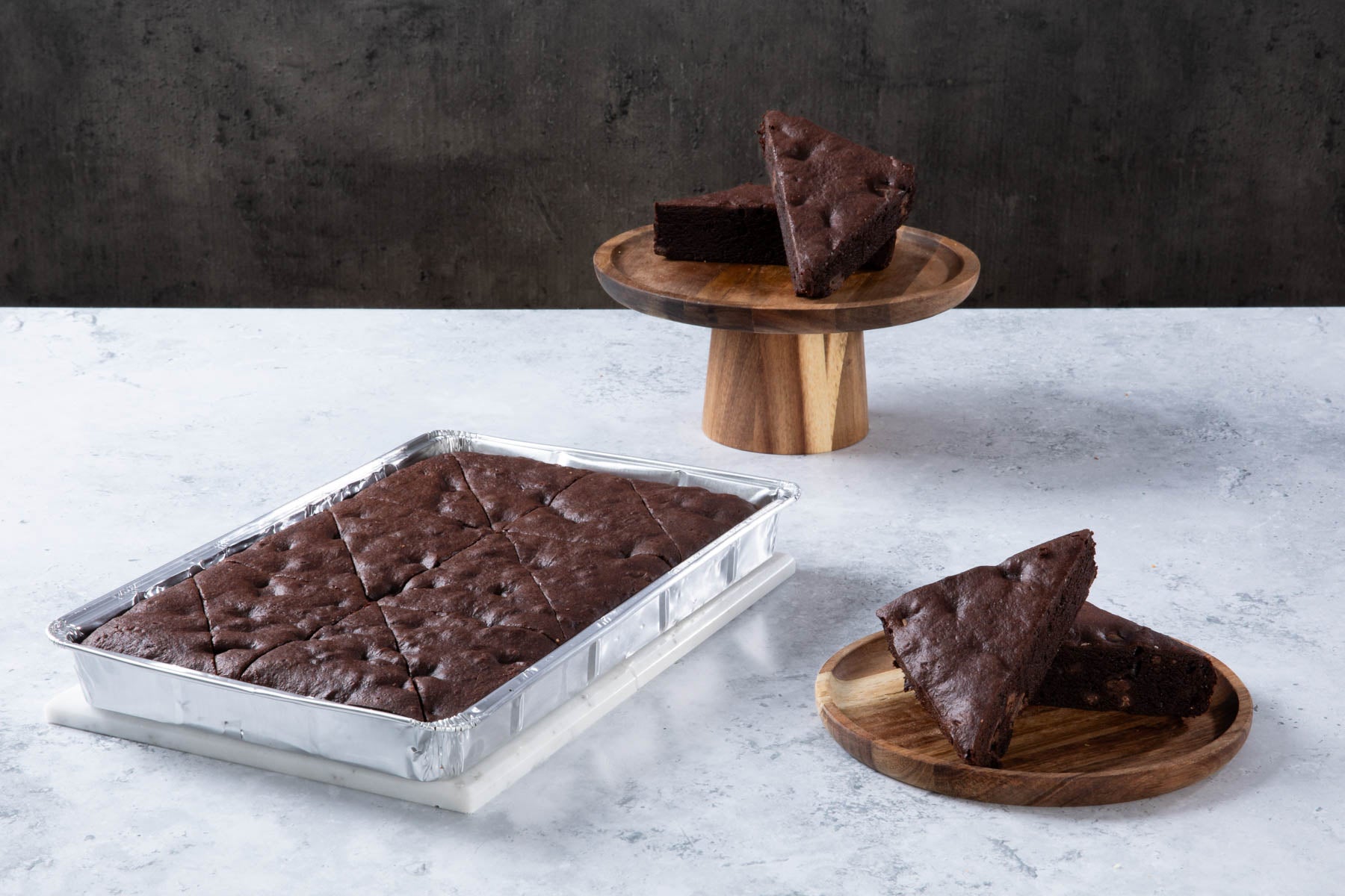 Chocolate cake with creamy frosting and chocolate topping on a wooden board.